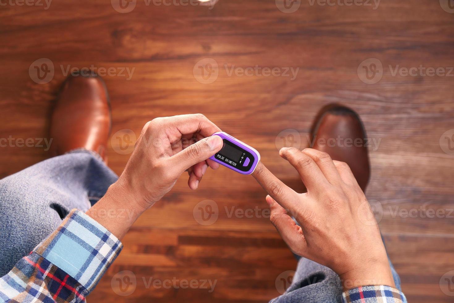 Männerhand mit einem Pulsoximeter foto