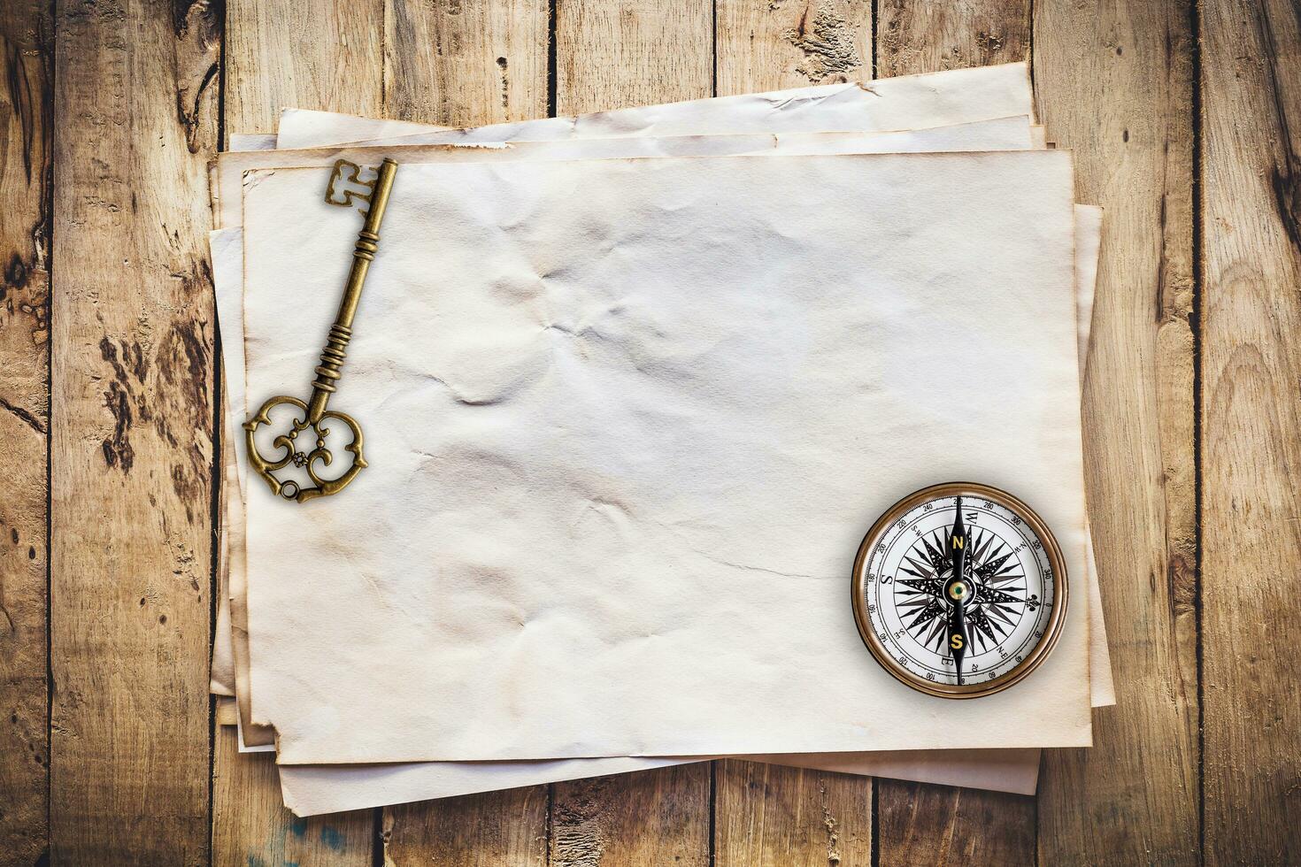 alt Schlüssel und Kompass auf alt Papier Jahrgang auf Holz Hintergrund mit Raum foto