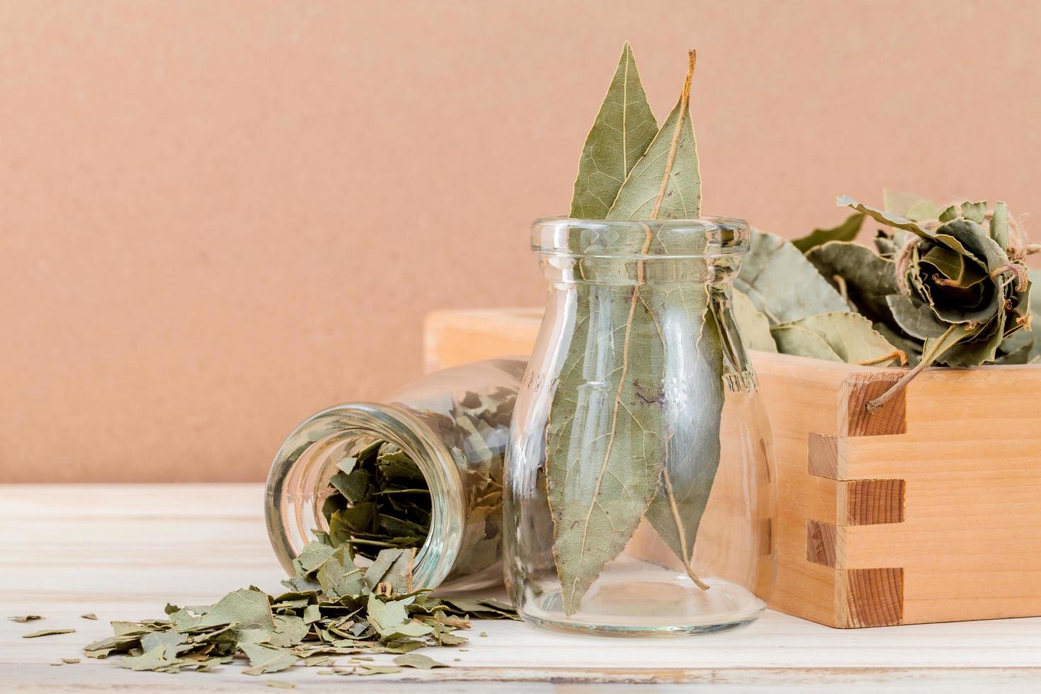 Flasche getrocknete Lorbeerblätter und eine Holzkiste foto