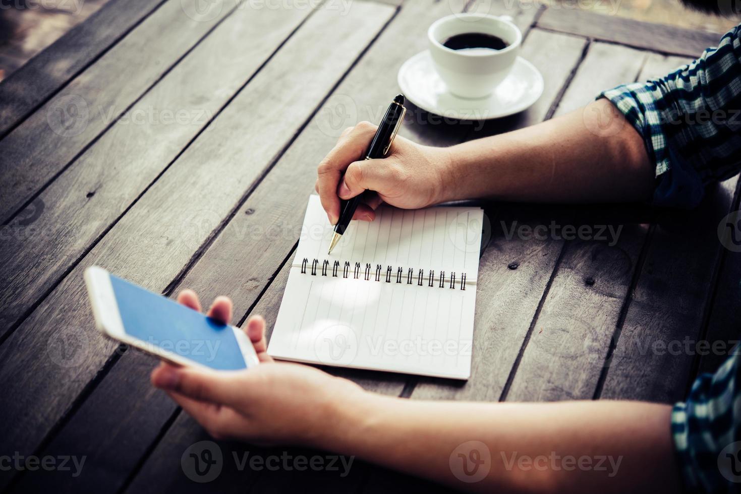 Nahaufnahme des Geschäftsmannes, der Smartphone während der Arbeit im Café verwendet foto