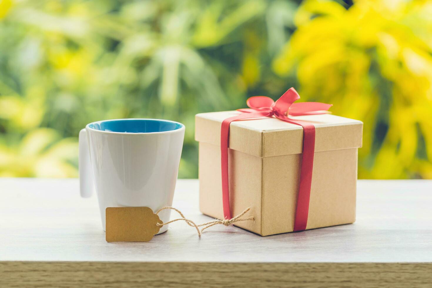 Kaffee Tasse und Geschenk Box auf Holz Tabelle mit Sonnenlicht. foto