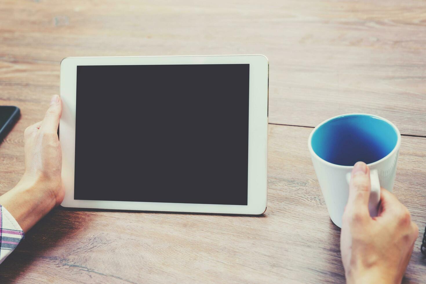 Hand Frau mit Tablette Computer auf hölzern Tabelle mit Jahrgang getönt. foto