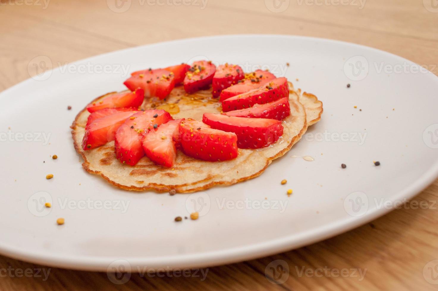 Erdbeerpfannkuchen auf einem weißen Teller auf einem Holztisch foto