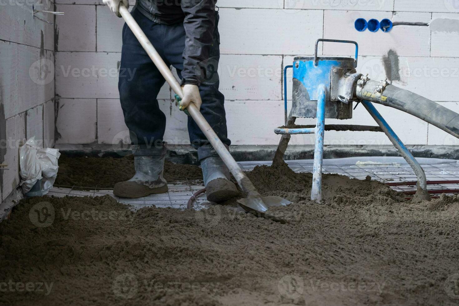 halb Trocken Fußboden Estrich - - ein Arbeiter Schaufeln ein Konstruktion Mischung durch ein Besondere Ärmel zum Zementierung und Nivellierung auf Unterflur Heizung Rohre. foto