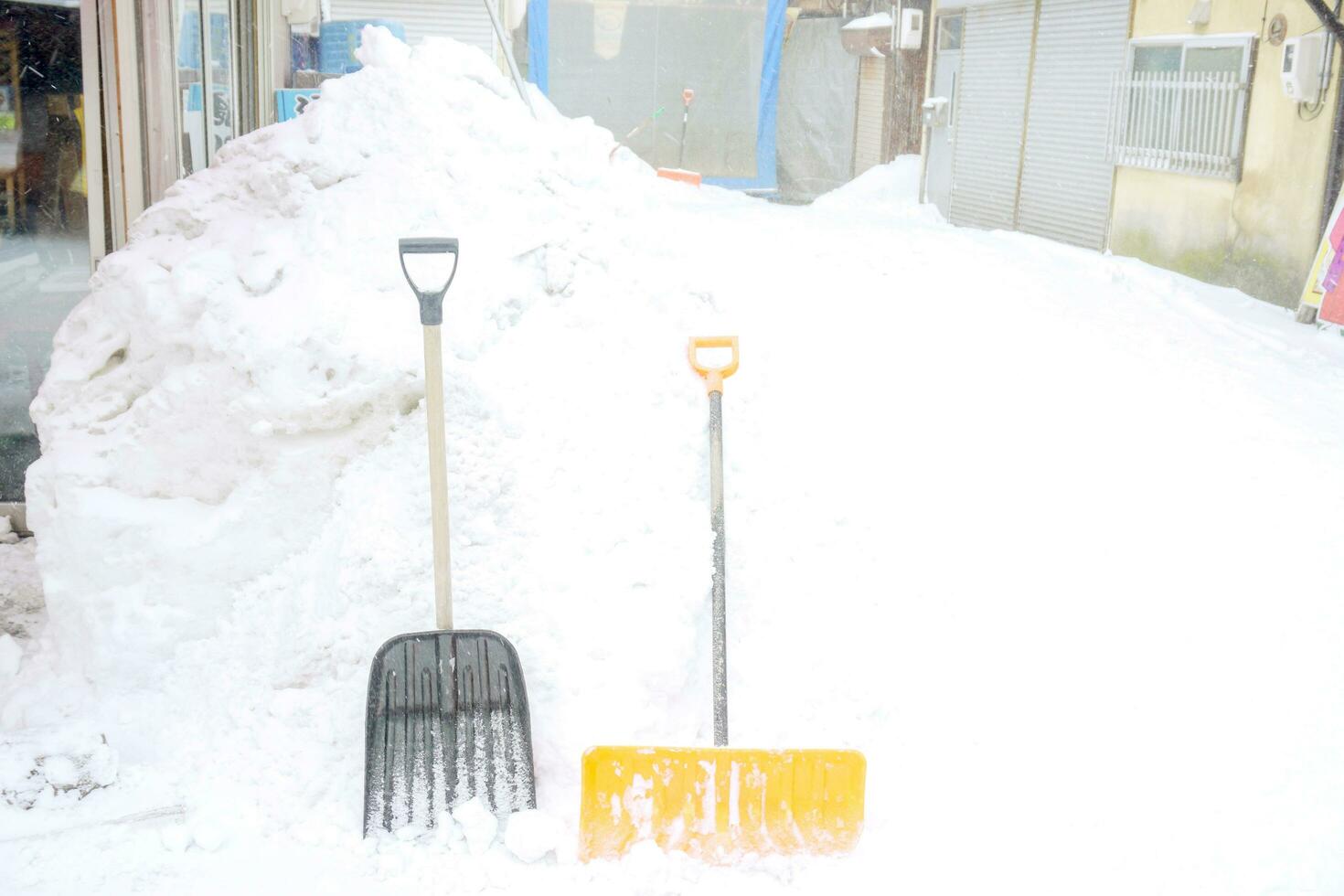 Schnee Scoop und Kehrmaschinen stellen im Vorderseite von ein groß Haufen Schnee. foto