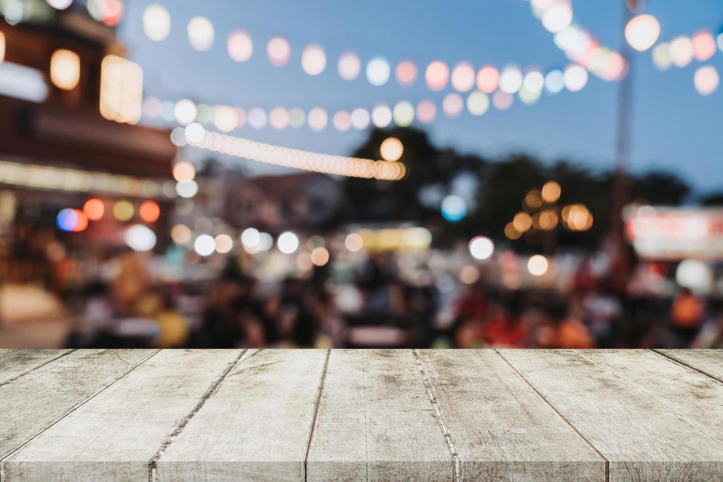 leeren hölzern Tabelle und verschwommen Hintergrund beim Nacht Markt Festival Menschen Gehen auf Straße mit Kopieren Raum, Anzeige Montage zum Produkt. foto