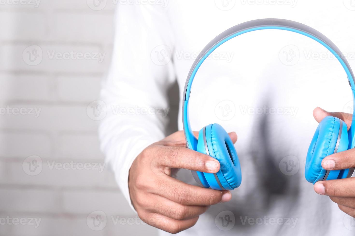 Mann hält blaue Kopfhörer foto