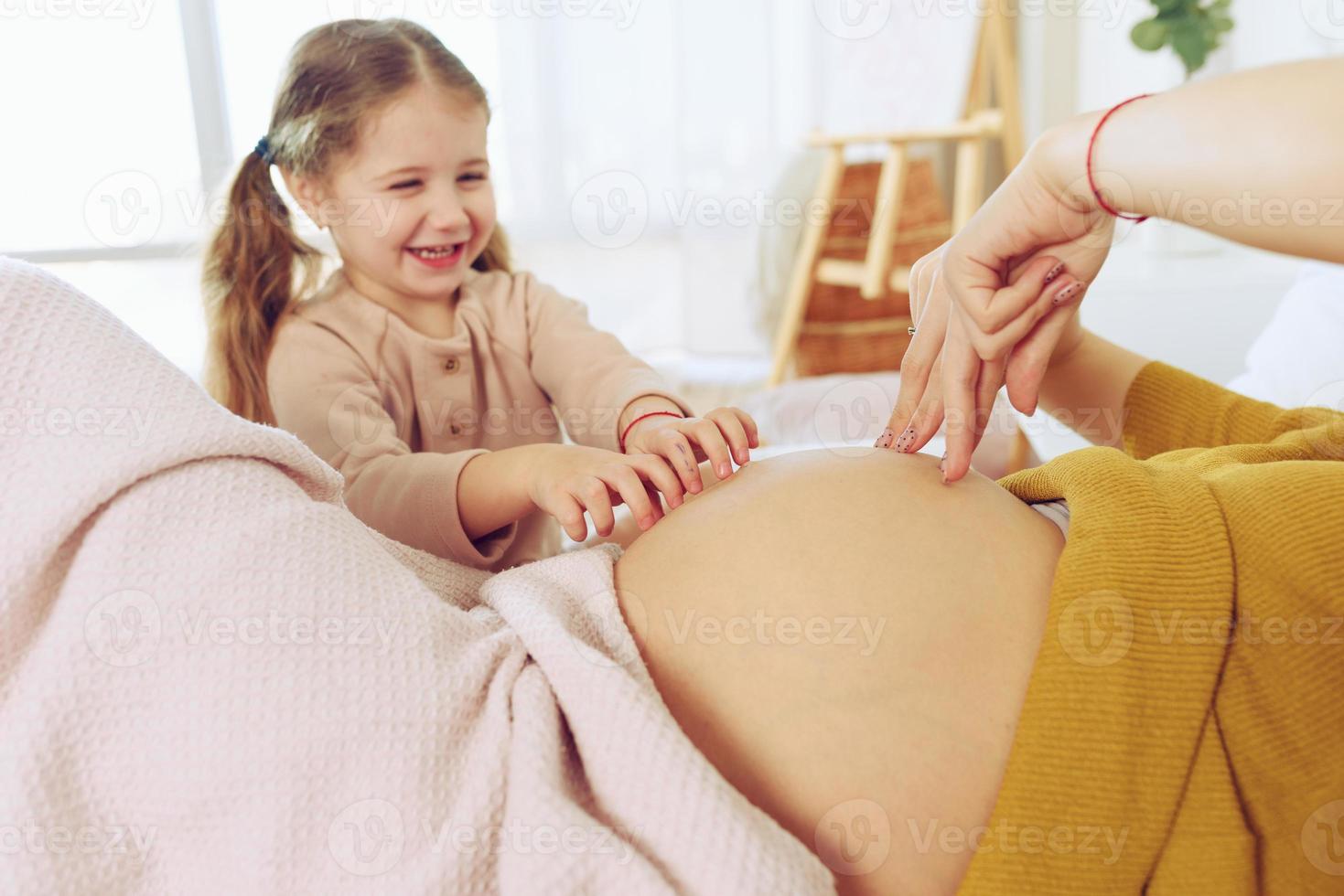 schwanger Mama Theaterstücke mit ihr Tochter. Konzept von Familie, Freude und Schwangerschaft foto
