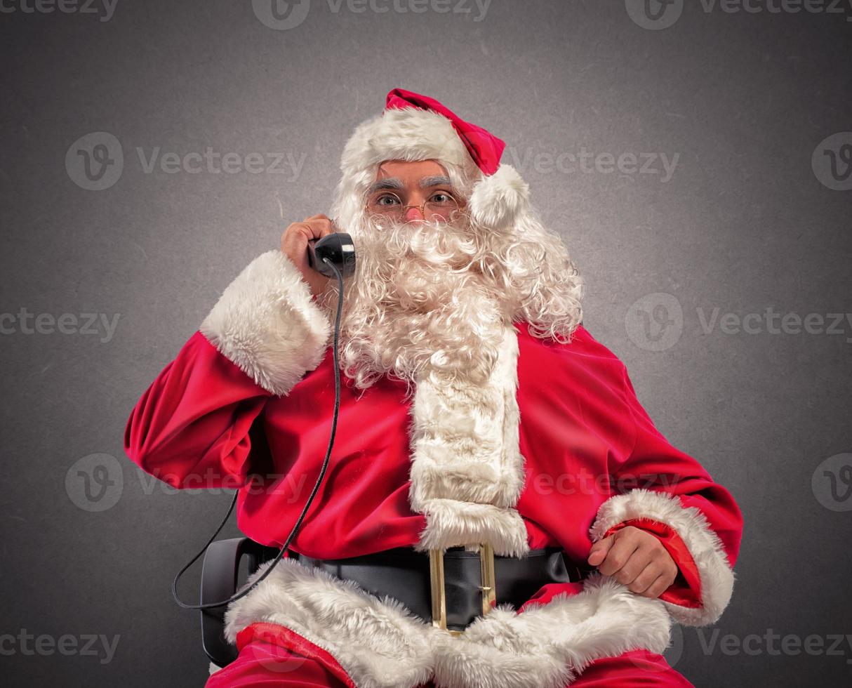 Santa claus erhält Anfragen über Telefon foto