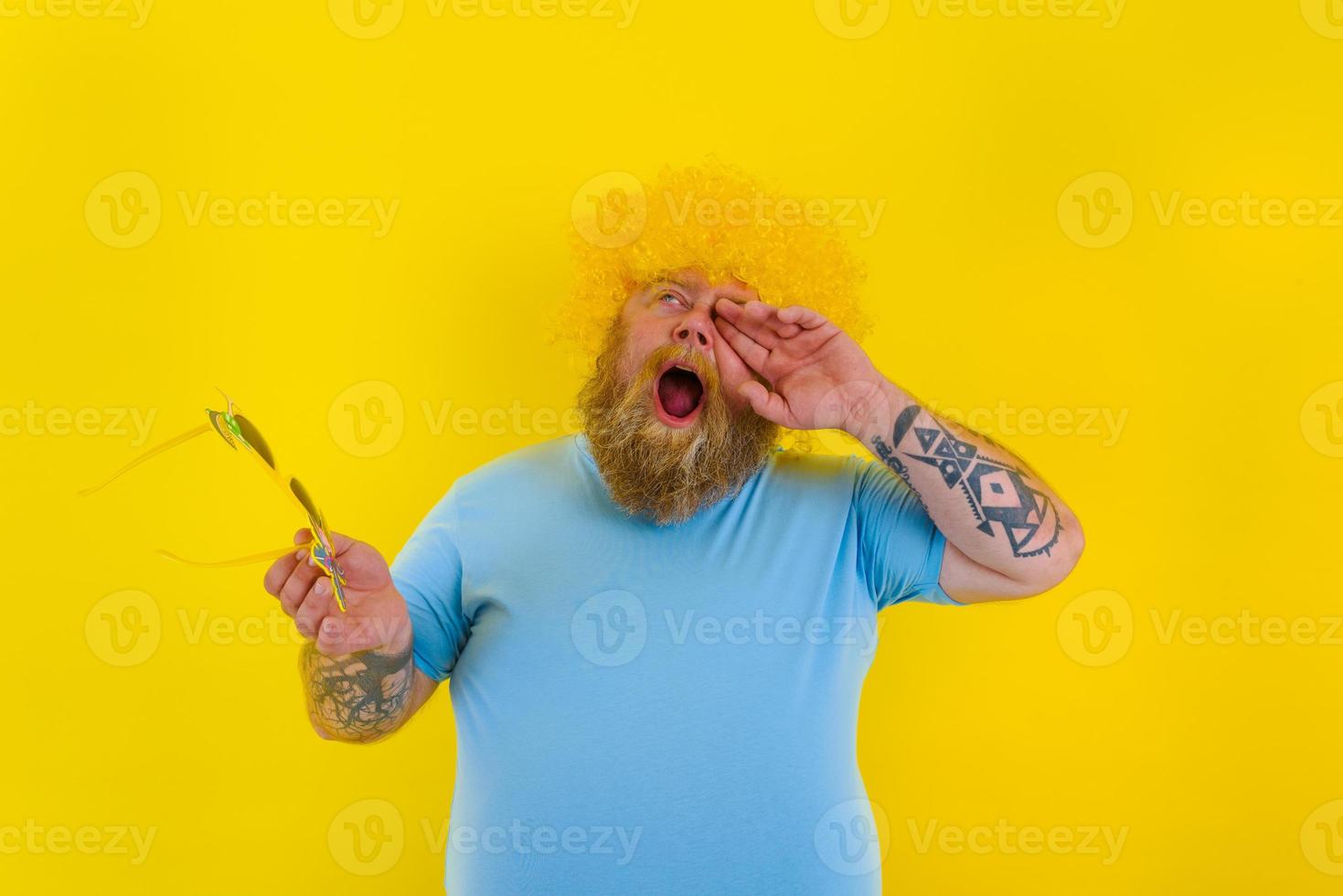 Fett genervt Mann mit Perücke im Kopf und Sonnenbrille foto