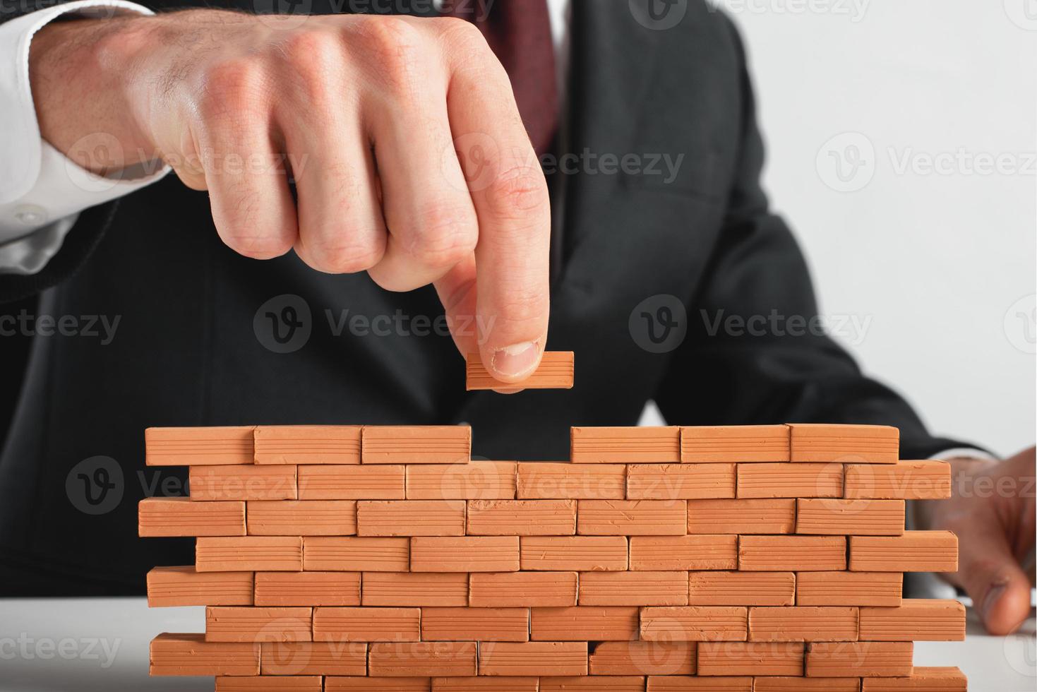Geschäftsmann setzt ein Backstein zu bauen ein Mauer. Konzept von Neu Geschäft, Partnerschaft, Integration und Start-up. foto