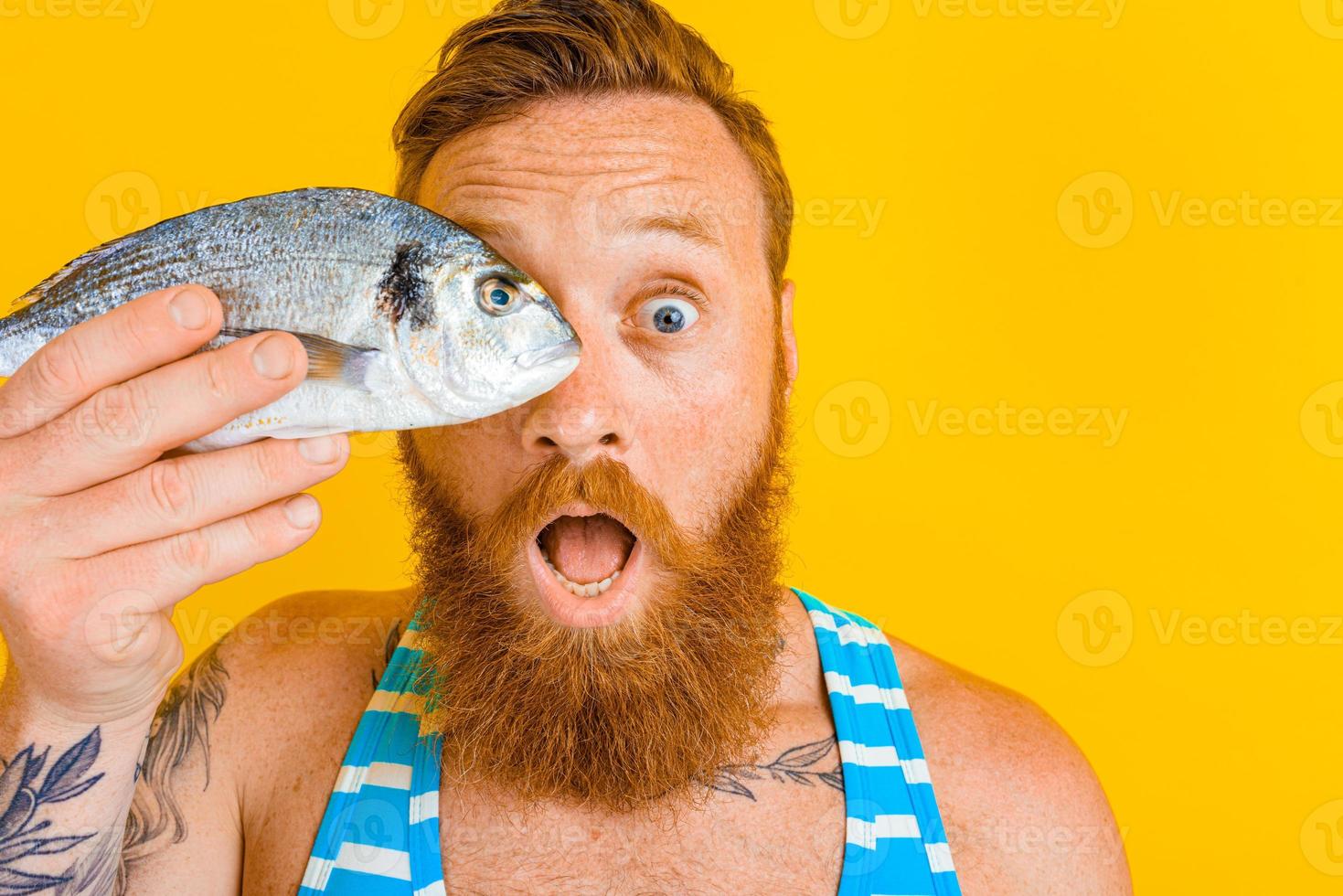 Mann mit Bart und Badeanzug gefangen ein Fisch foto