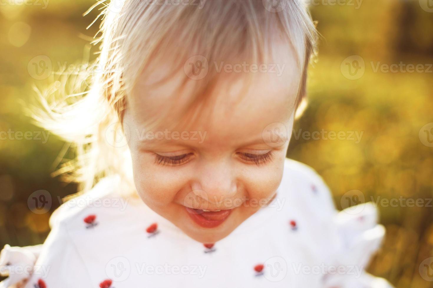 Porträt von ein wenig glücklich Mädchen draussen . das Kind lächelt und zeigt an das Zunge foto