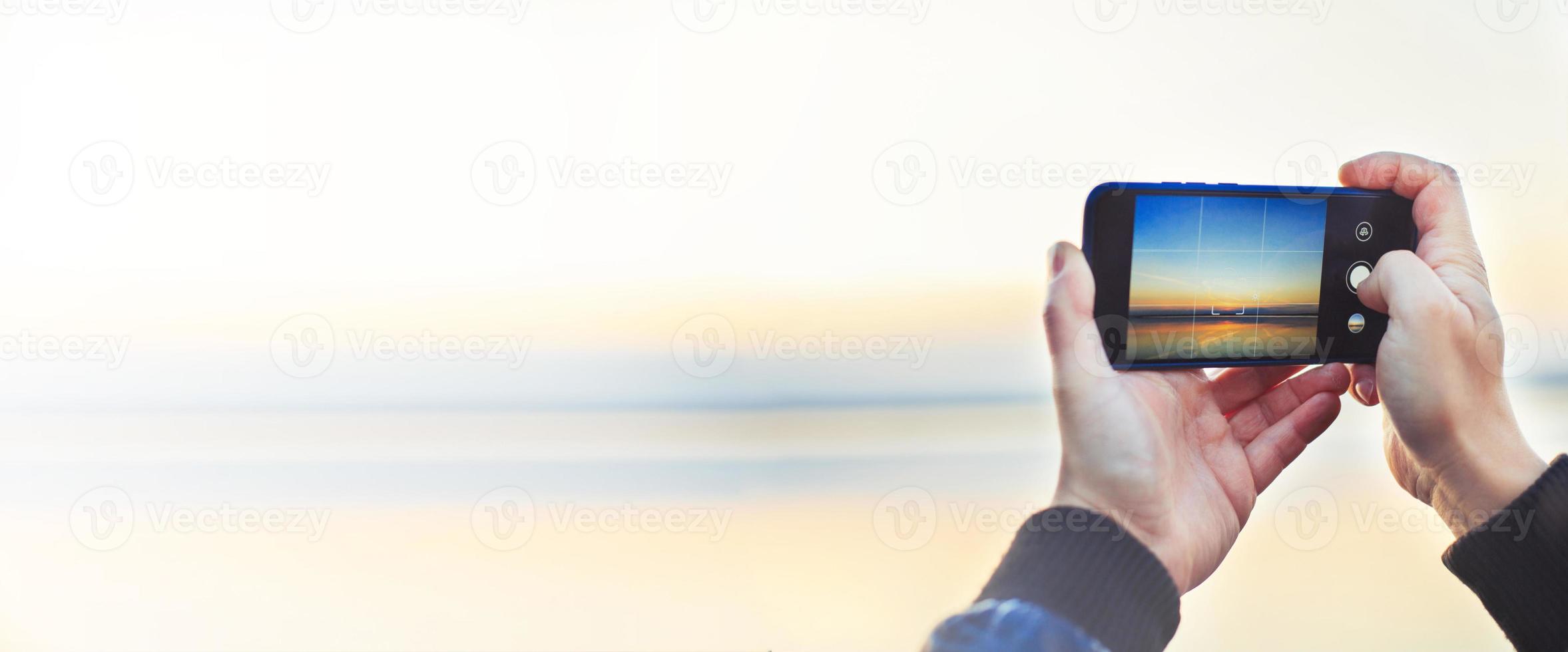 ein Mann nehmen ein Foto von das schön Sonnenuntergang auf seine Telefon