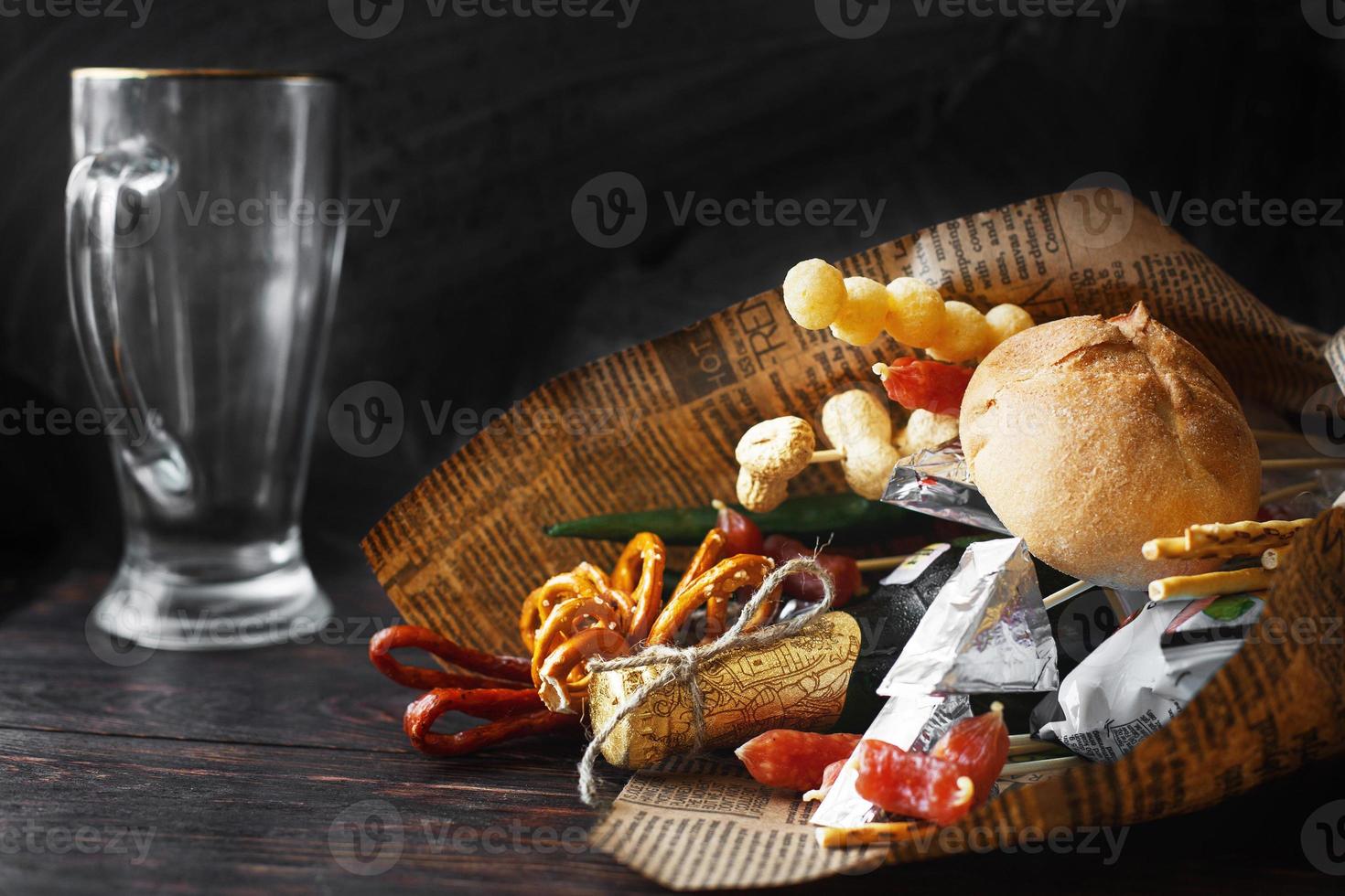 ein können von Bier mit ein Snack auf ein hölzern dunkel Hintergrund mit ein leeren Bier Glas. Geschenk Strauß zu ein Mann foto