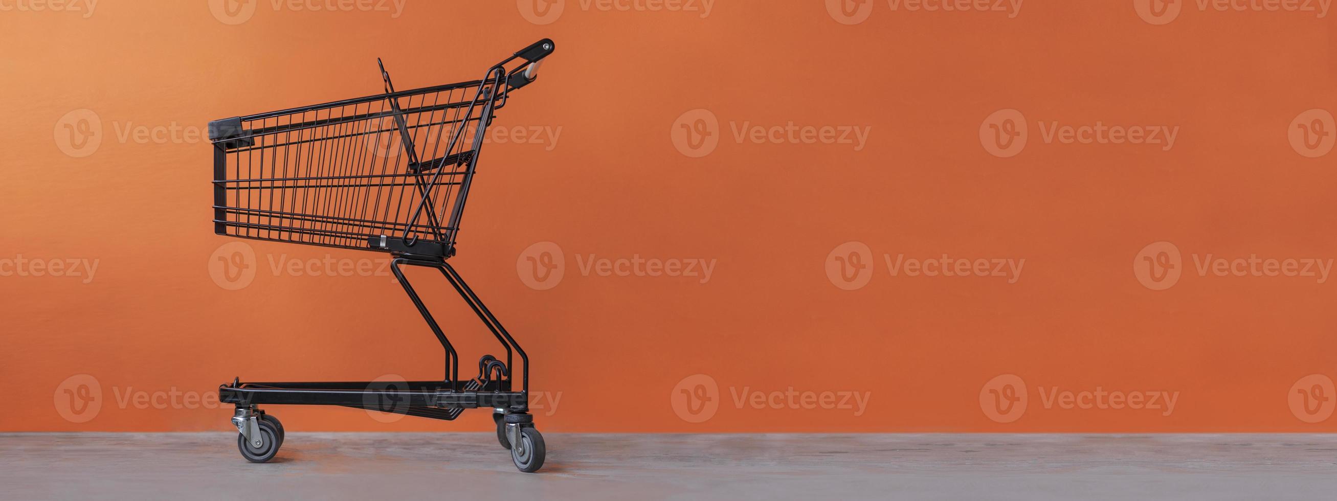 Einkaufswagen auf einem orangefarbenen Hintergrund foto