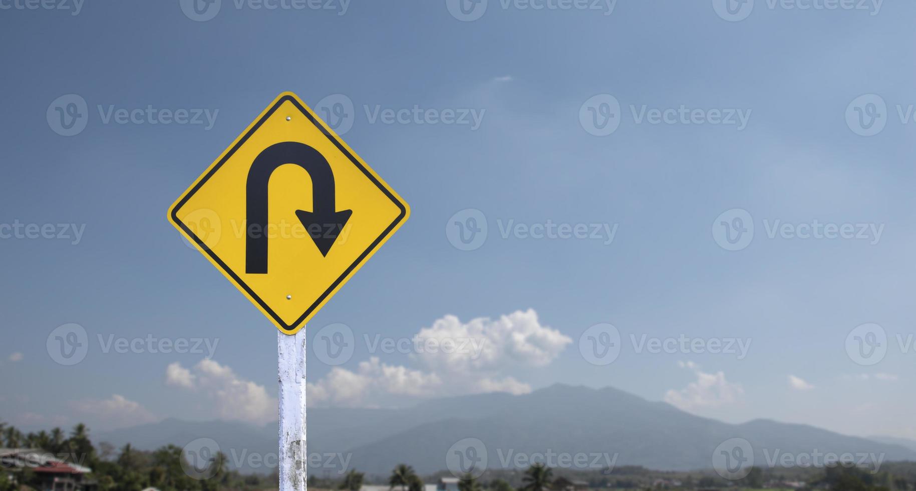 Verkehrsschild, rechts abbiegen auf Zementpfosten neben der Landstraße mit weißem bewölktem Bluesky-Hintergrund, Kopierraum. foto