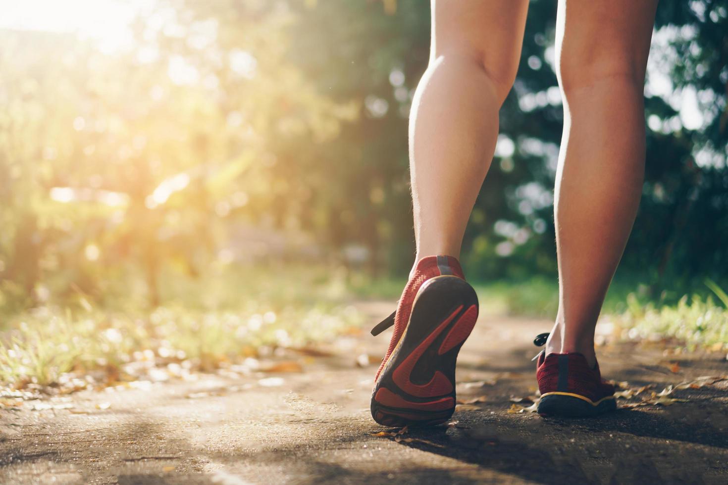 Frau, die Laufschuhe trägt und auf grünem Hintergrund der Natur läuft foto