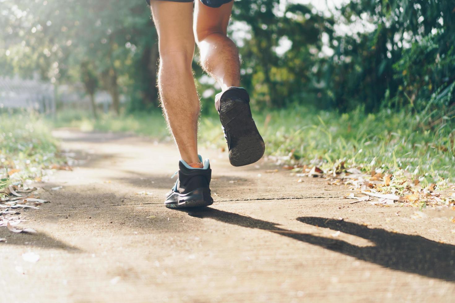 Frau, die Laufschuhe trägt und auf grünem Hintergrund der Natur läuft foto