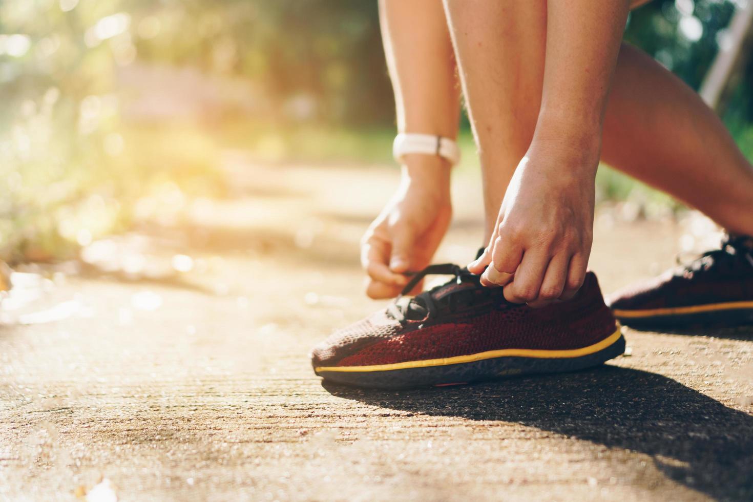 Frau, die Laufschuhe trägt und auf grünem Hintergrund der Natur läuft foto