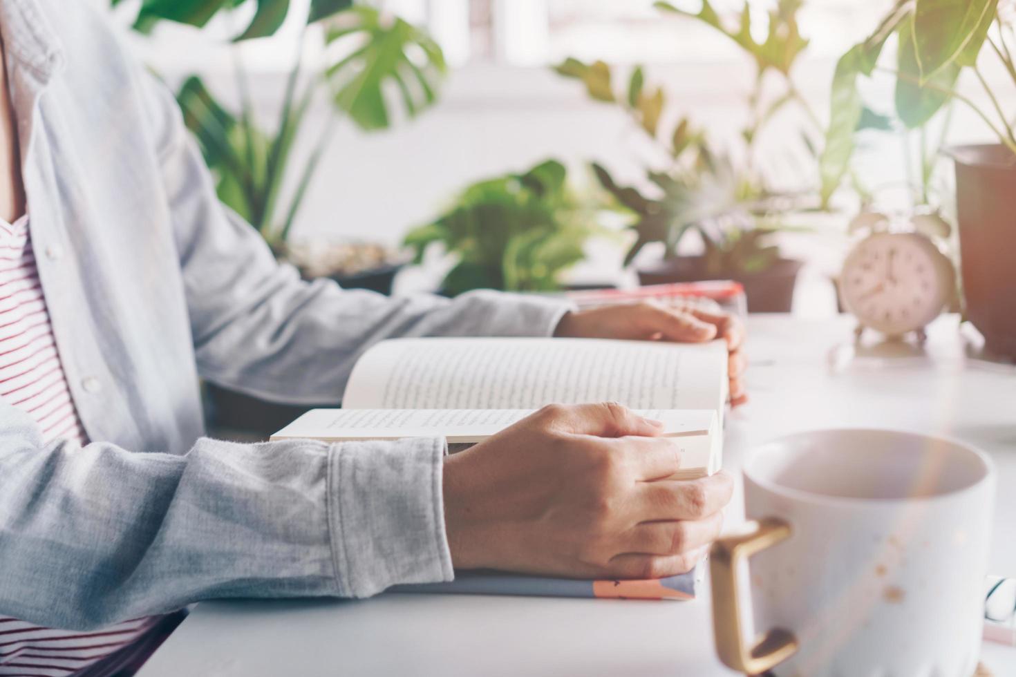 Frau, die ein Buch im Arbeitsbereich mit Naturhintergrund liest foto