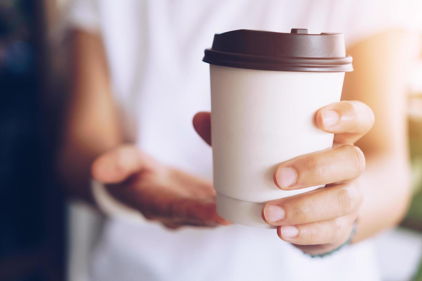 Hand hält eine Tasse Kaffee mit Sonnenlicht Fackel foto