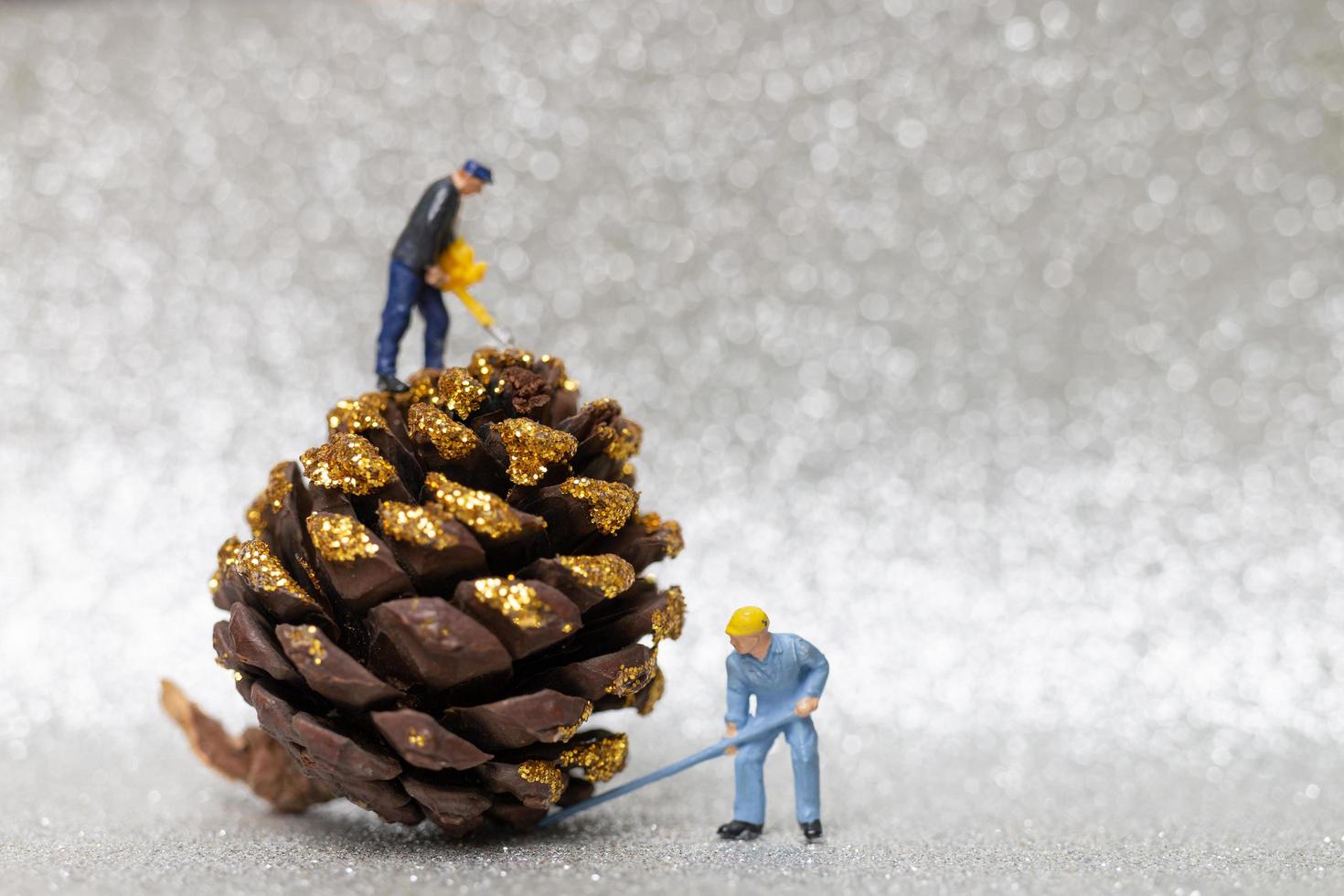 Miniaturarbeiter, die einen Weihnachts-Tannenzapfen, Weihnachten und ein frohes neues Jahr-Konzept vorbereiten foto