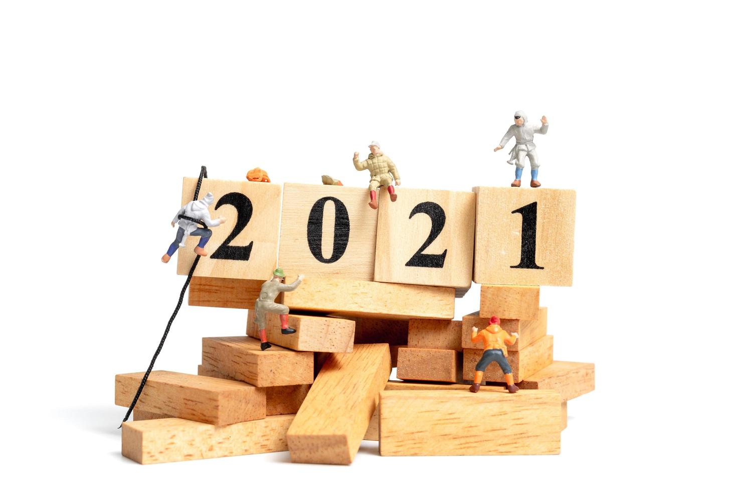 Gruppe von Miniaturmenschen, die auf Holzwürfel mit den Nummern 2021 klettern foto