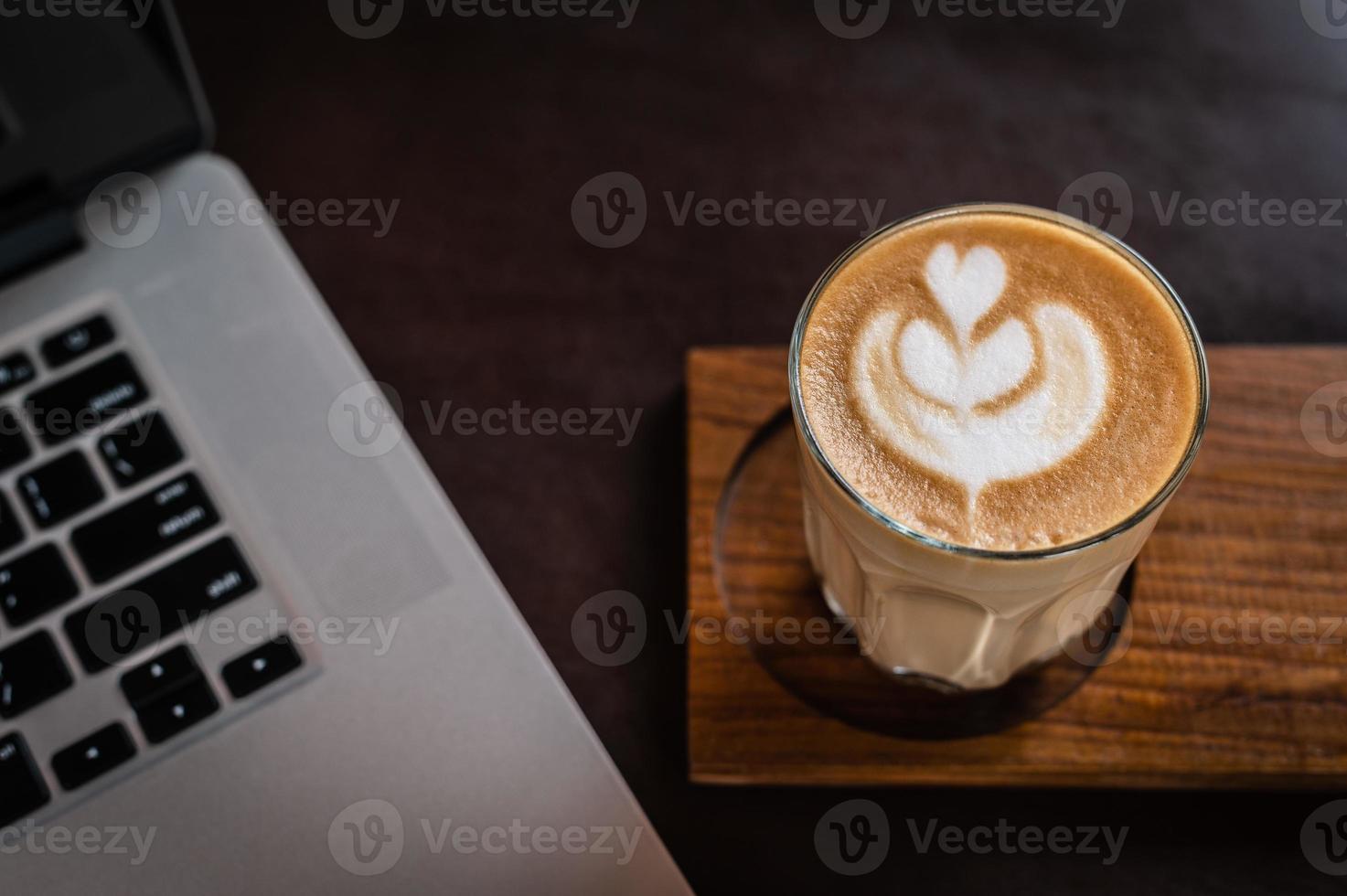 Latte in einem Glas auf einem Holzschreibtisch foto