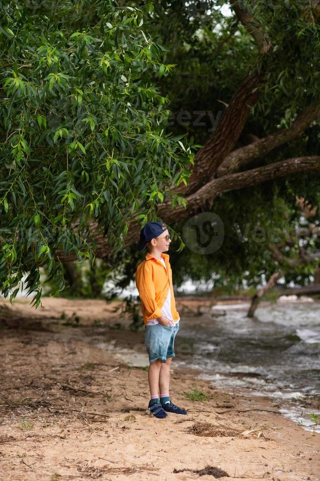 ein Junge im ein Orange Hemd auf das Strand foto