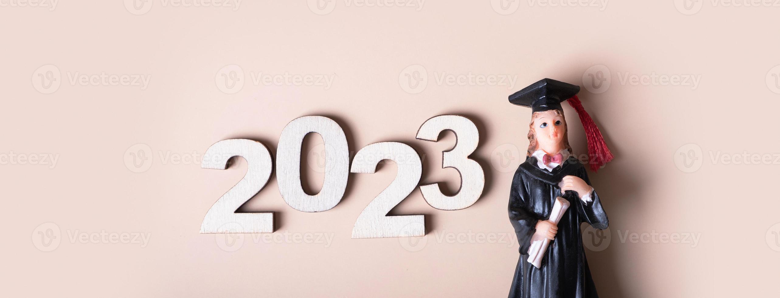 Klasse von 2023 Konzept. hölzern Nummer 2023 mit Absolvent Statuette auf Beige Hintergrund foto