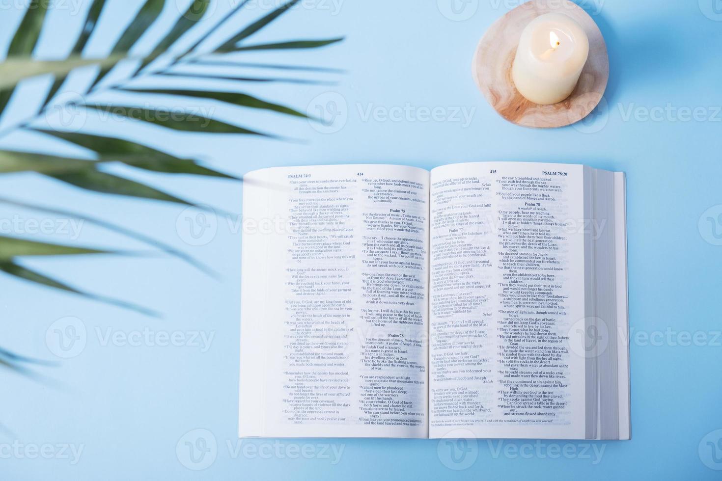 offene bibel mit kerzen und palmblättern auf blauem hintergrund foto