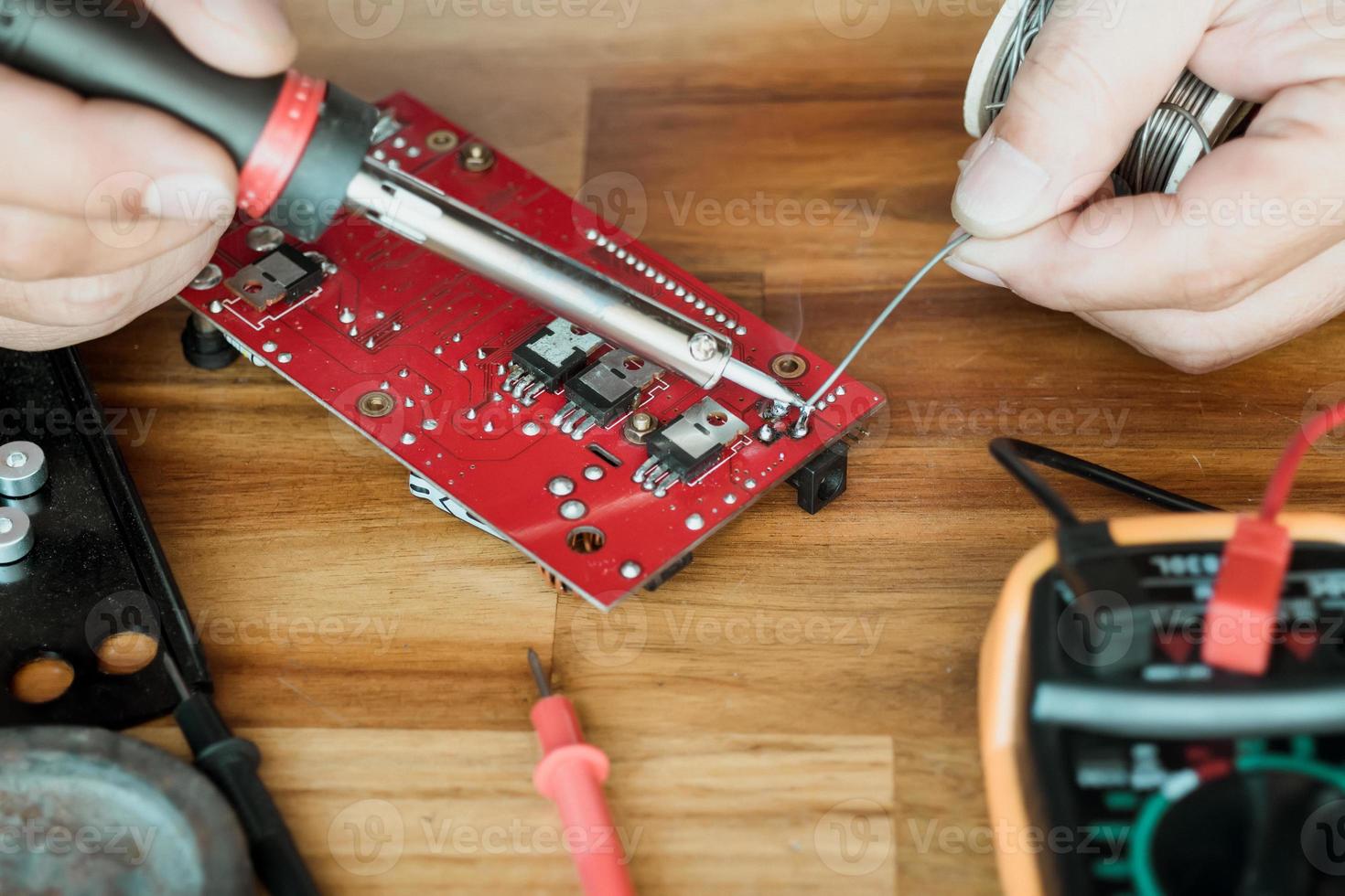 Techniker Mann halten Eisen löten und reparieren das Schaltkreis Tafel durch Löten. elektrisch Arbeit Konzept foto