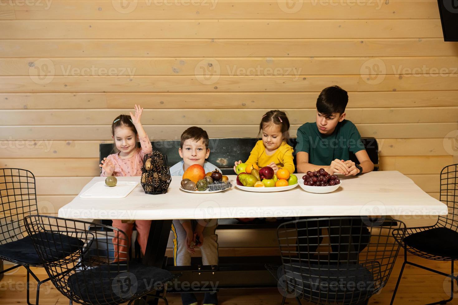 vier Kinder Essen Früchte im hölzern Land Haus auf Wochenende. foto