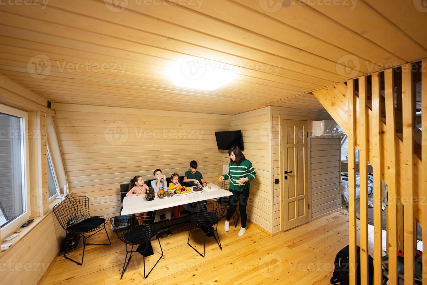 Mutter mit vier Kinder Essen Früchte im hölzern Land Haus auf Wochenende. foto