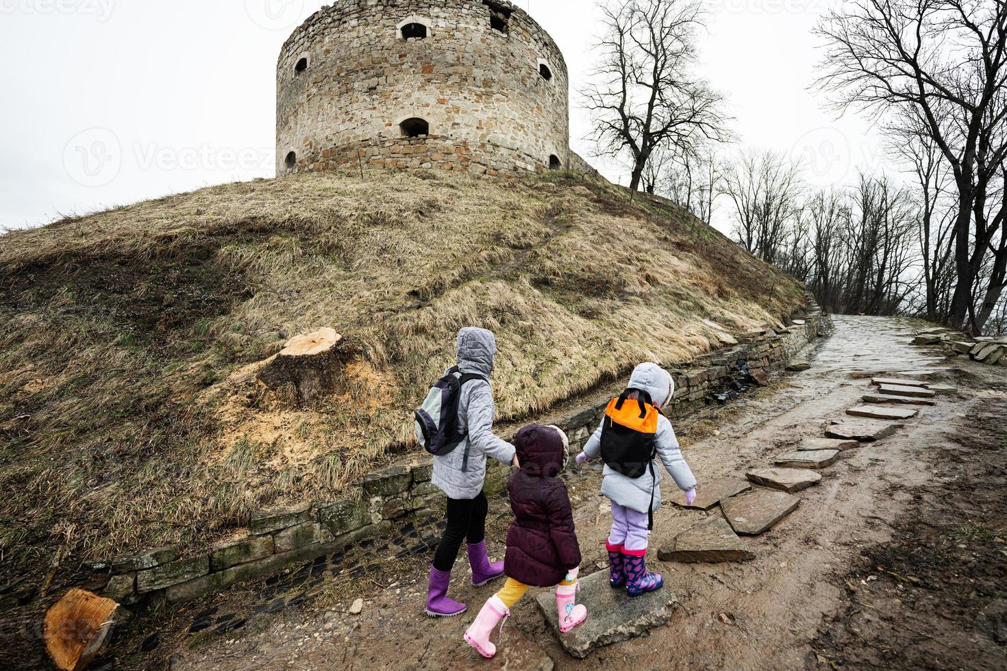 Mutter und Mädchen gehen oben das nass Pfad zu ein uralt mittelalterlich Festung im Regen. Terebovlia Schloss, Ukraine. foto