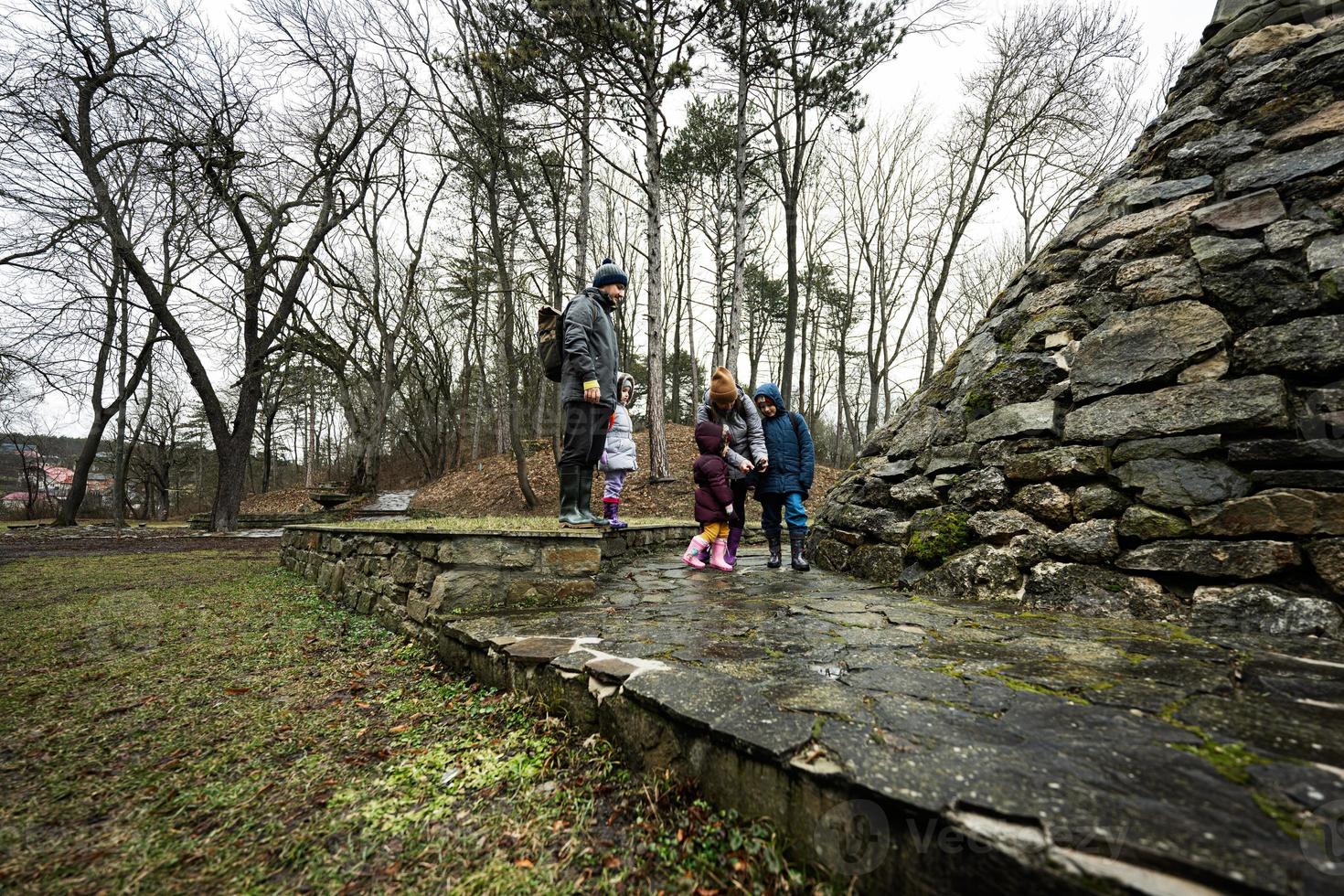 Familie Tourist mit drei Kinder, Stand in der Nähe von Stein Monument im Wald. foto