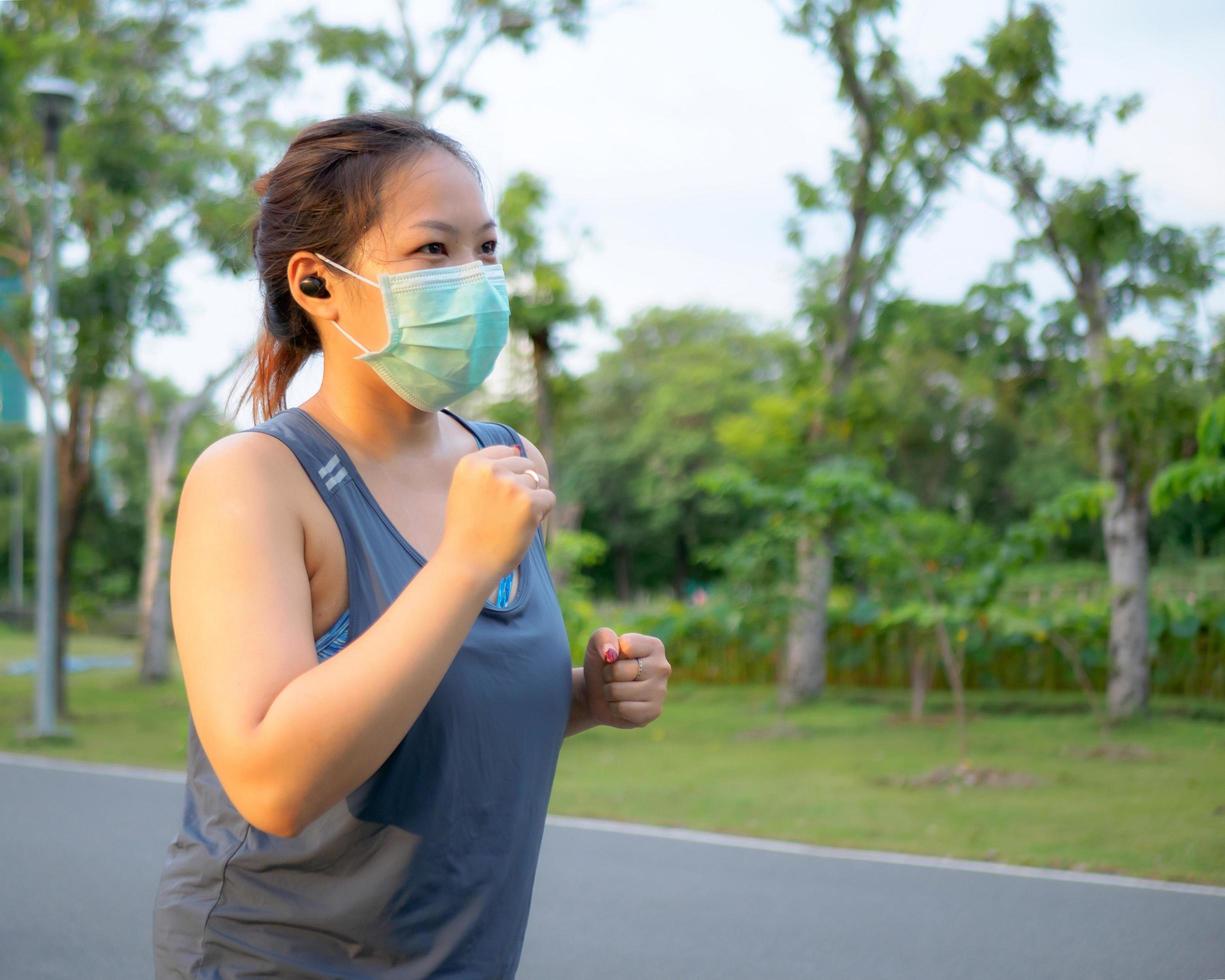 Porträt von ein schön asiatisch Frau im Sportbekleidung, Stehen mit ihr zurück, Dehnen Vor ausüben draussen im das Park im das Morgen zu leisten ein gesund Lebensstil. gesund Erwärmen oben foto