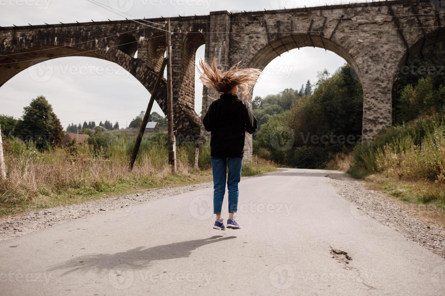 jung Frau Gehen in der Nähe von alt Viadukt. Tourist Mädchen im Landschaft Landschaft durch das historisch verlassen Eisenbahn Bogen Brücke Viadukt im Worochta, Iwano-Frankiwsk Region, Ukraine foto