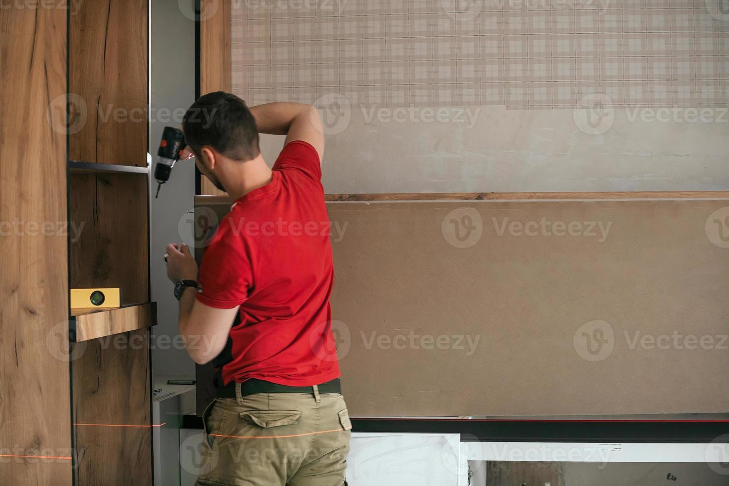 Handwerker, Möbel Hersteller und Monteur, installiert ein modern Küche im das Haus mit Werkzeuge im Hand. Benutzerdefiniert Möbel Konzept, Zuhause Verbesserung, Renovierung foto