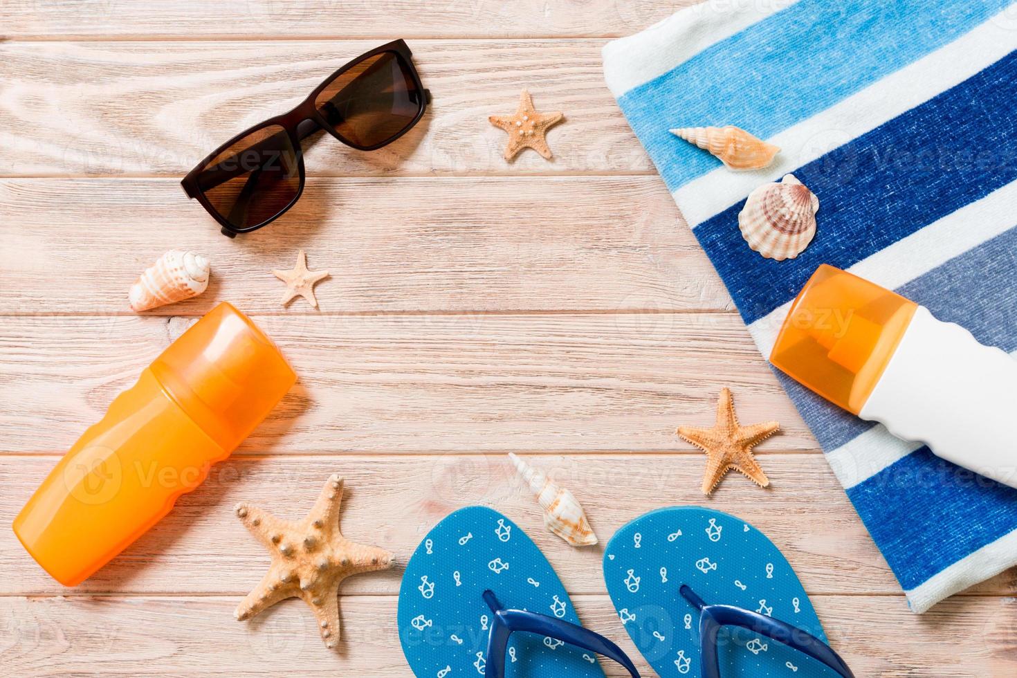 Flipflops, Strohhut, Starfish, Sonnenschutzflasche, Körperlotionsspray auf Draufsicht des hölzernen Hintergrundes. flach lag sommerstrand meer zubehör hintergrund, vaation konzept foto