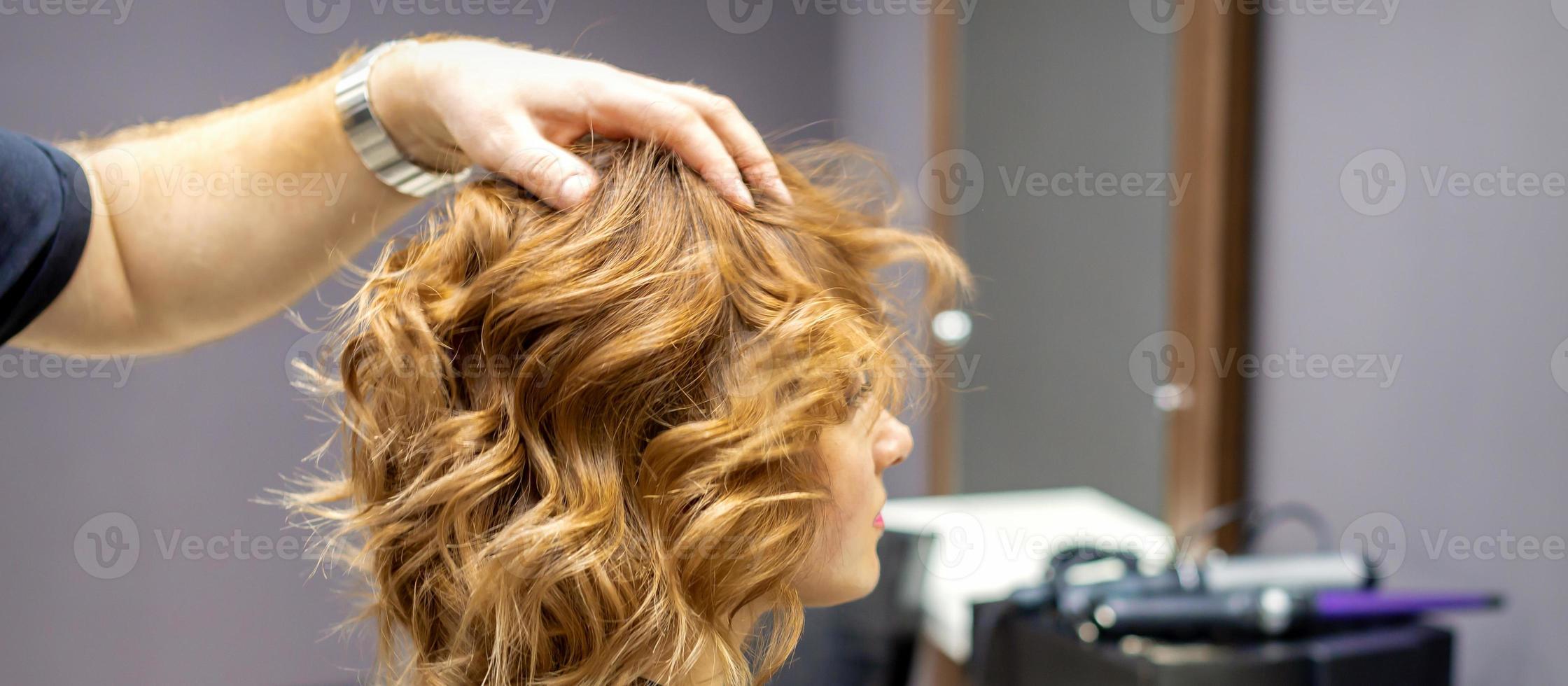 Friseur prüft lockig Frisur von Frau foto