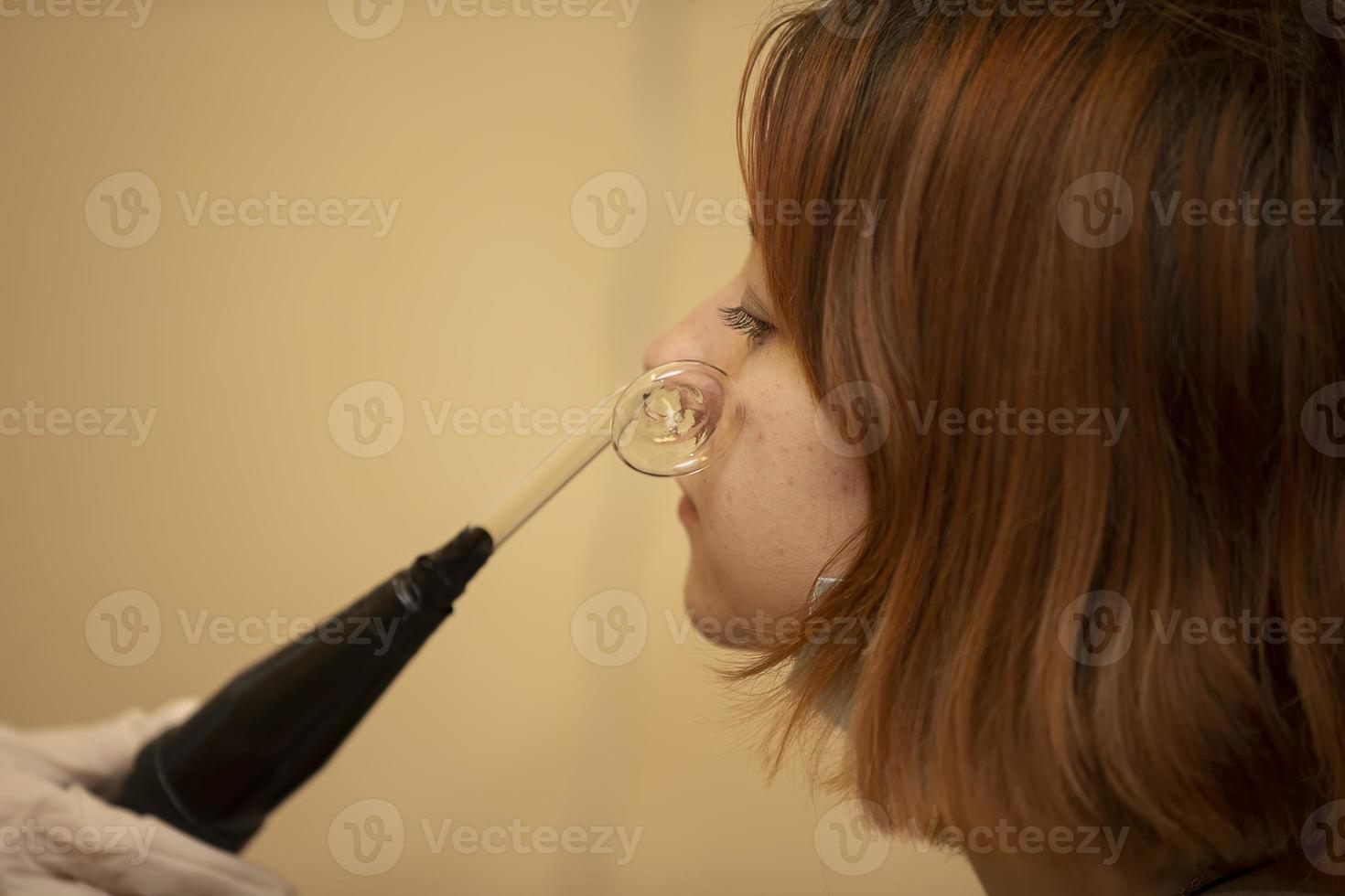 kosmetisch Gerät darsonval. Gesichts- Reinigung Verfahren. Salon Haut Pflege. Fachmann Ausrüstung zum Dermatologie. Entfernung von Akne im ein Teenager Mädchen. foto