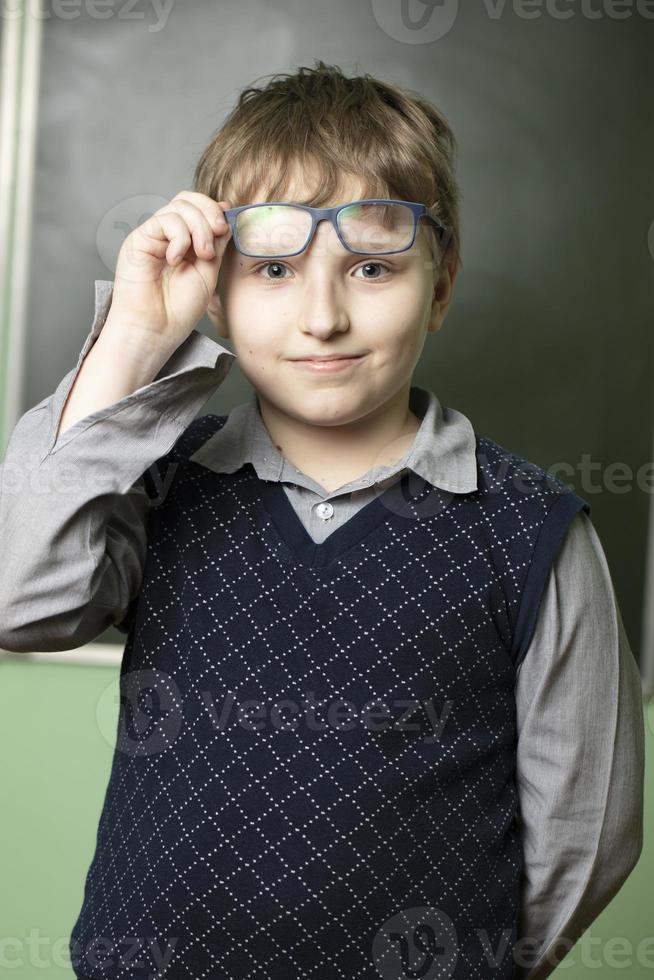 Porträt von ein komisch Schüler im Brille beim das Tafel. zehn Jahr alt Schüler im Klasse. foto