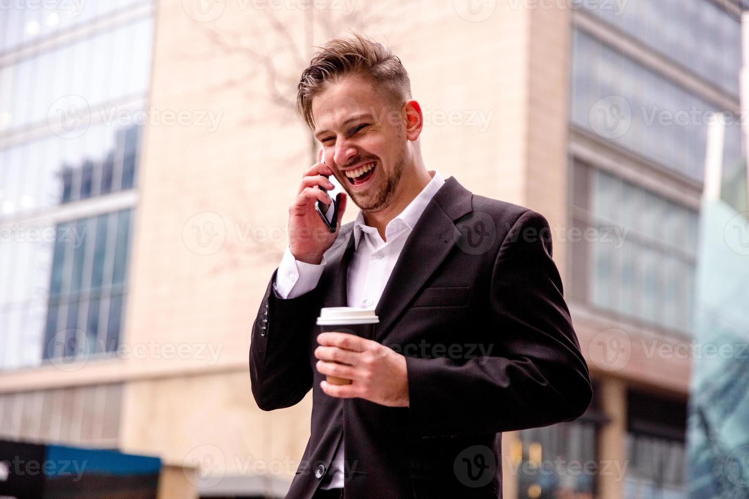 Kerl im ein passen spricht auf das Telefon lacht und Spaziergänge mit Kaffee im seine Hände Nahansicht foto