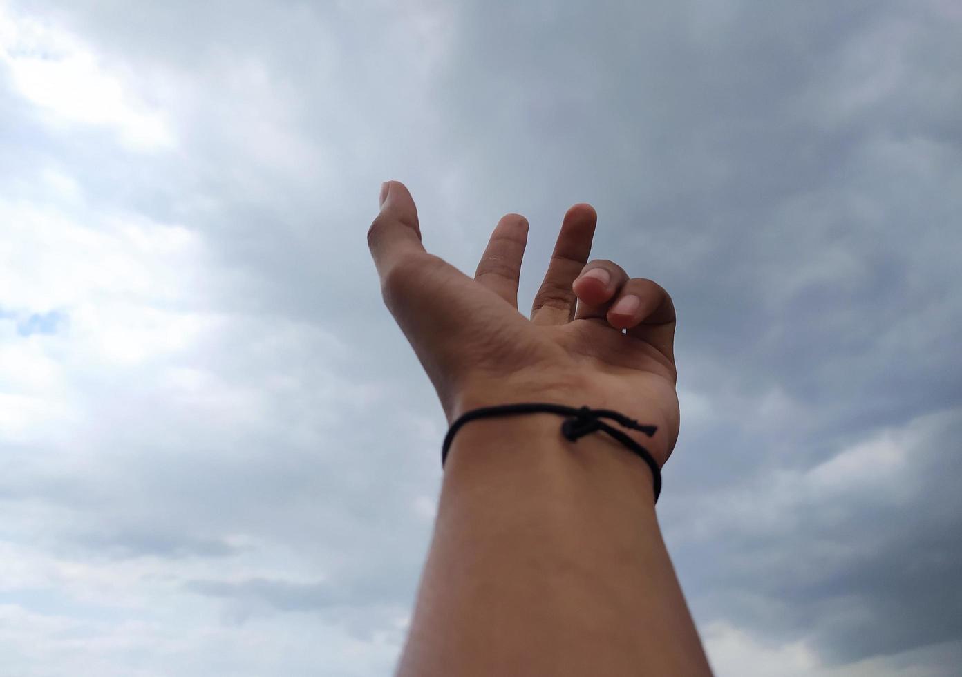 Mann erziehen Hand greifen etwas von das hell Blau Himmel foto