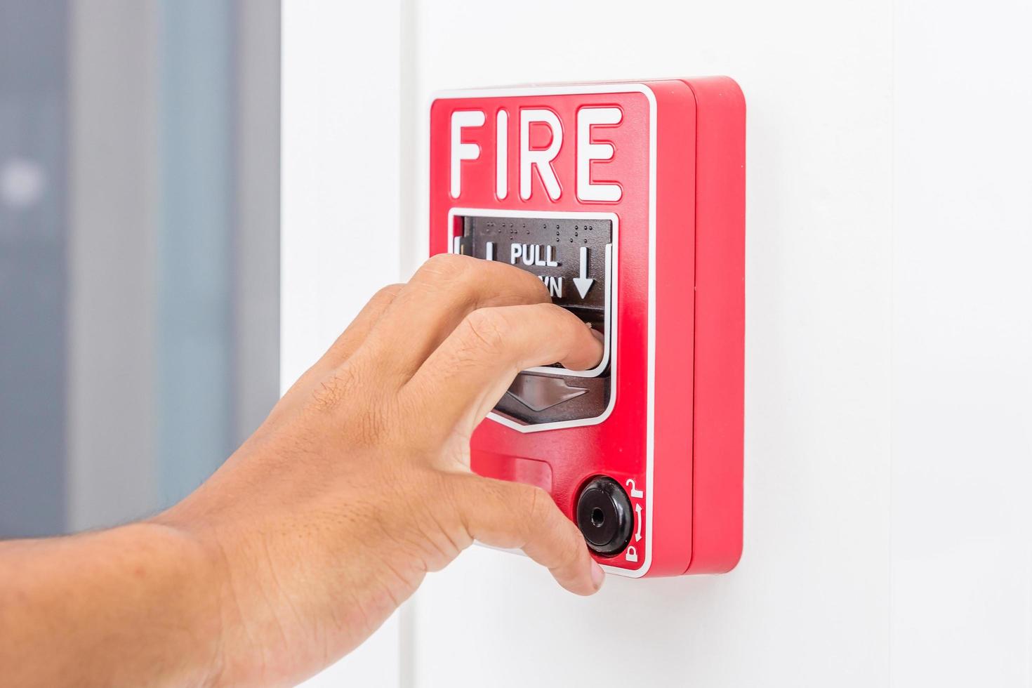 Hand des Mannes, der Feueralarmschalter zieht foto