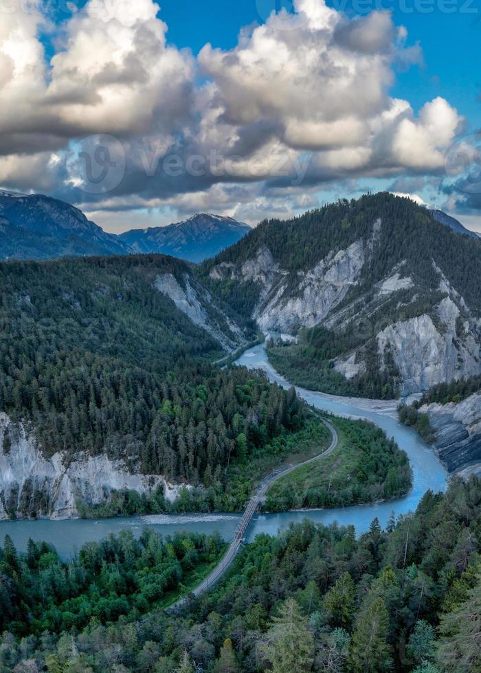 ein Fluss Das läuft im ein s Kurve zwischen das Berge, a Eisenbahn Brücke Kreuze das Fluss foto