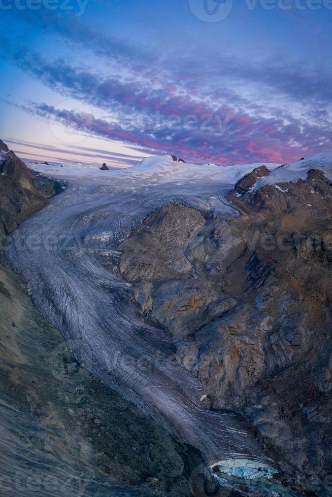 ein enorm Berg Gletscher während Sonnenuntergang mit lila Wolken foto