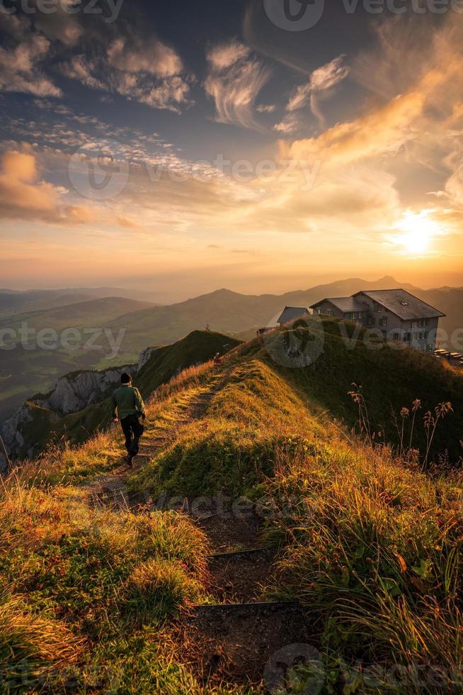 Sonnenaufgang auf ein Berg ,A Mann Gehen auf ein Wandern Weg gegenüber Haus foto